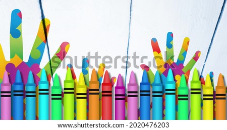 Image of colourful crayons over hands formed with puzzles. autism and learning difficulties awareness and support concept digitally generated image.