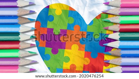 Image of colour pencils over heart formed with puzzles. autism and learning difficulties awareness and support concept digitally generated image.