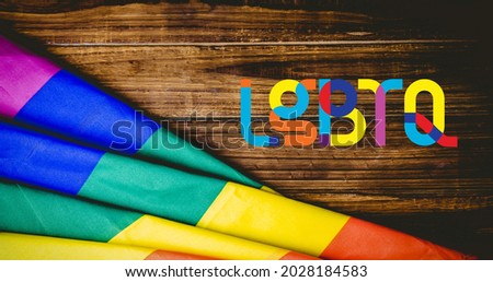 Lgbtq text and rainbow flag over wooden boards. lgbtq pride and equality celebration concept digitally generated .