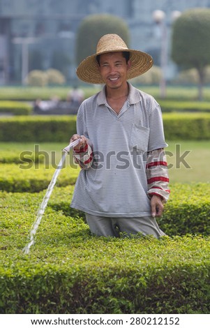 GUANGZHOU, GUANGDONG PROVINCE, CHINA - OCTOBER 12, 2006: Man watering plants in park in  city of Guangzhou.