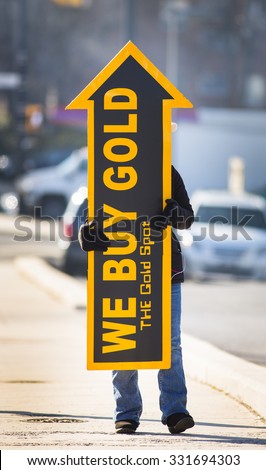 ARLINGTON, VIRGINIA, USA - FEBRUARY 21, 2013: Woman holds We Buy Gold sign on sidewalk to attract customers.