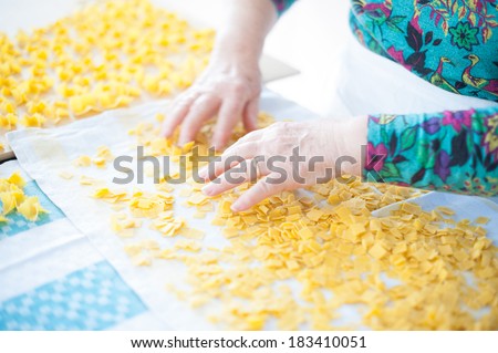 Woman's hands touch and mix up fresh hand-made pasta to dry it on a napkin.