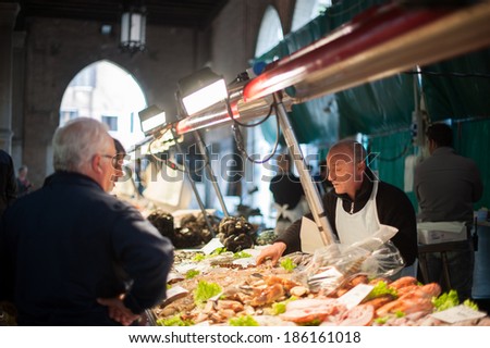 VENICE, ITALY - APRIL 1, 2014: An unidentified merchant sells fish at the fish market to unidentified customers, on April 1, 2014 in Venice, Italy.