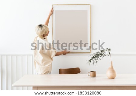 Woman hanging a photo frame on a white wall mockup Stockfoto © 