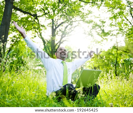 Businessman sitting in a forest with his laptop.