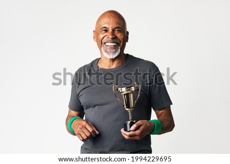 Sporty senior man holding a golden trophy