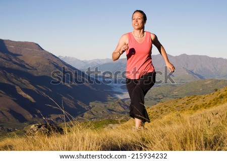 Young woman jogging in the wilderness with mountain range as a background.