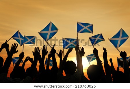 Group of People Waving Scottish Flags in Back Lit