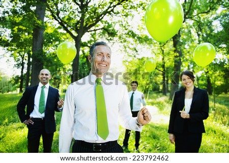 Eco-friendly business people holding green balloons in the woods.