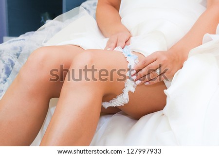 Bride putting a wedding garter on her leg