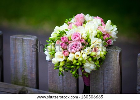 Wedding bouquet with roses and freesia on rustic country fence