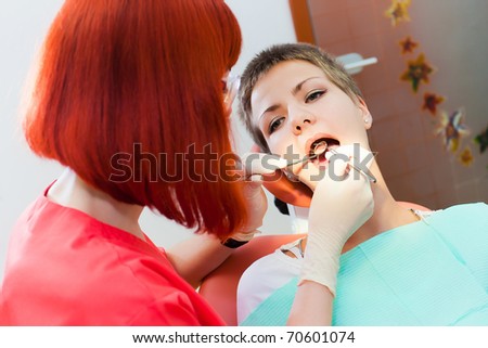 Image of young lady with dentist over her checking oral cavity