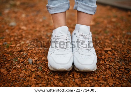 White female sneakers on walks in the park on a background of pebbles