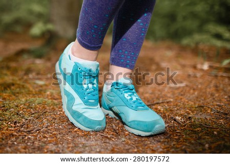 Women\'s sports sneakers on a background of forest trails in summer
