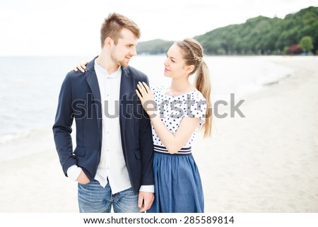 European couple relaxing on the sea beach hugging each other and talking
