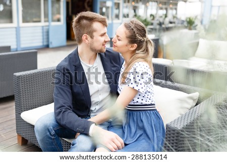 A young couple spends time on the couch in the outdoor cafe near the Baltic Sea