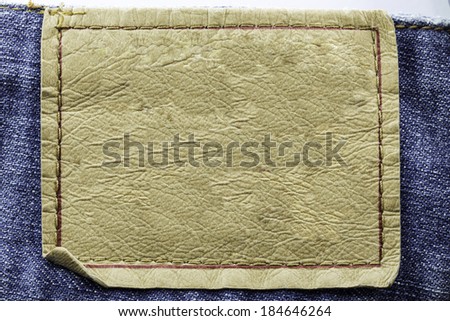 Blank leather jeans label sewed on a blue jeans isolated on white background