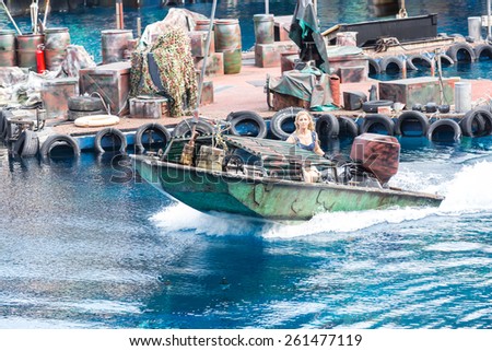 SINGAPORE - JANUARY 30, 2015 :  Undefined Stuntman in action shooting the machine gun on the warship in the live stunt show called Waterworld at Universal Studios Singapore.