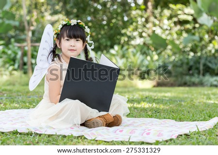Little asian girl read book with smiling face in the park