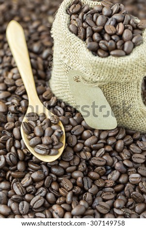 coffee beans in sack bag and spoon on roasted coffee seed background