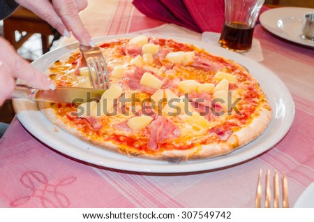 A tasty Pizza Hawaii on a white plate in a local Italian pizzeria.