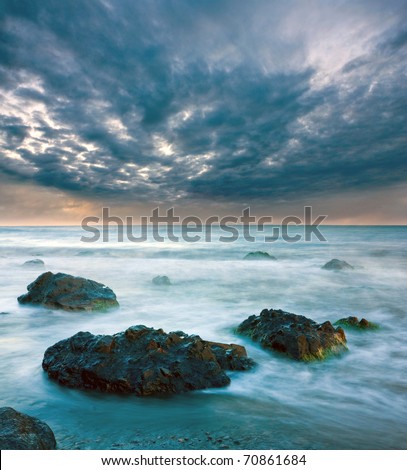 Sea landscape with stones in water before storm