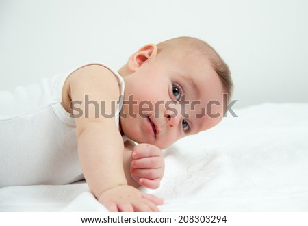 Cool hand raise of a little baby boy while laying on his stomach and holding his head upwards looking sideways curious