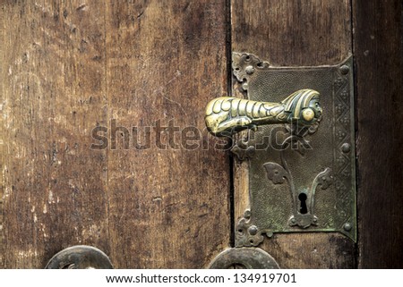 old bronze door handle with wooden door in te background