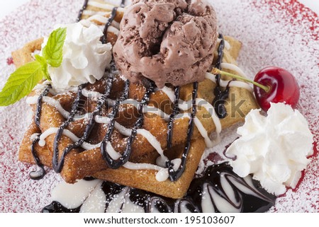Belgian waffle with chocolate syrup whipped cream and chocolate ice cream with red cherry