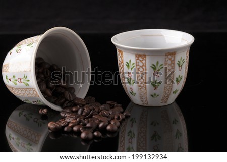 Hand painted traditional arabic coffee cups on black background and coffee  beans with reflection