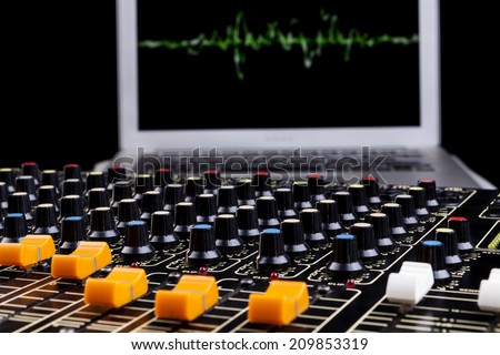 Analog studio sound mixer closeup with laptop and sound wave form in the background