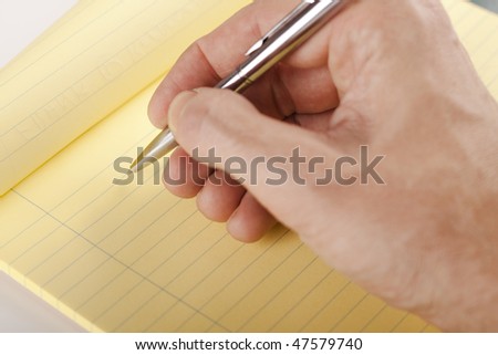 hand writing on yellow page with a silver colored pen