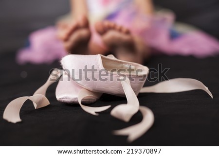 Pink ballerina baby shoes with girl feet in the background