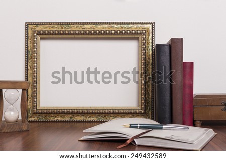 Landscape golden frame with books and hourglass on wood table