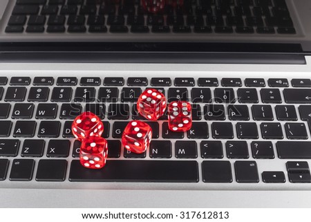 Red casino dices with chips on silver laptop with black Keyboard