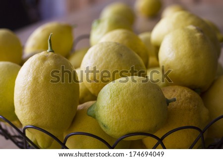 Group lemons freshly picked from the garden, on black iron fruit bowl on top of a wooden table
