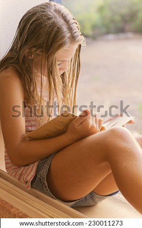 Black and white photo,twelve-years old, girl, caucasian, long hair girl reading a book in the window
