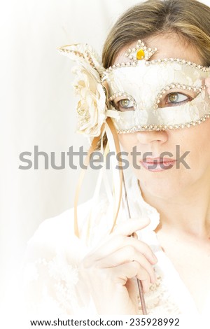 portrait of attractive caucasian woman holding a beautiful Venetian mask, photography in high key, very soft and elegant pose tones.