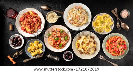 Pasta. Assortment of Italian pasta dishes, including spaghetti Bolognese, penne with chicken, tortellini, ravioli and others, shot from the top on a black background Stockfoto © 