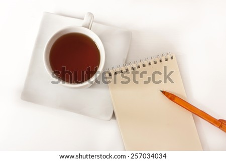 A notepad with a bright pen and a cup of tea on a white background with a place for text