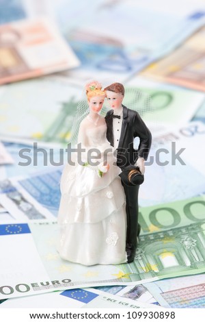 Wedding expense concept - wedding figurines (bride and groom) and money.