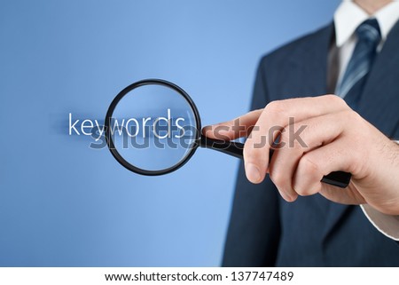 Keywords analysis, look for, search for and seek concept. Man with magnifying glass and text keywords.