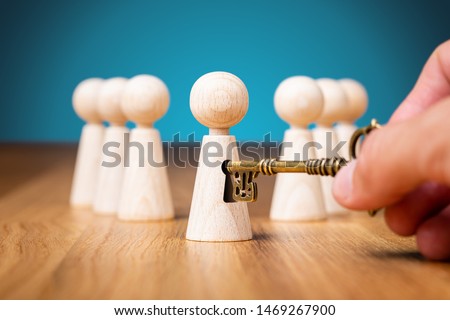 Coach unlock potential - motivation concept. Coach (manager, mentor, HR specialist) unlock leader potential and talent represented by wooden figurine and hand with key.