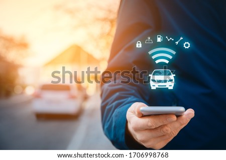 Intelligent car app on smart phone concept, intelligent vehicle and smart cars concept. Person with smart phone on street, car in background and wireless communication with car.