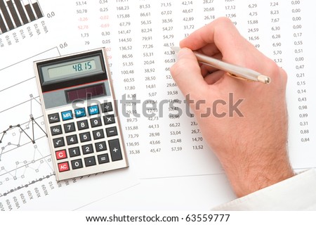 Business analyst - hand with pen; calculator, sheet and graph from top view