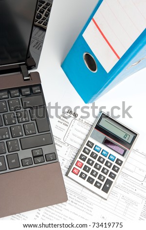 Tax form, part of laptop, calculator, office folder and pen