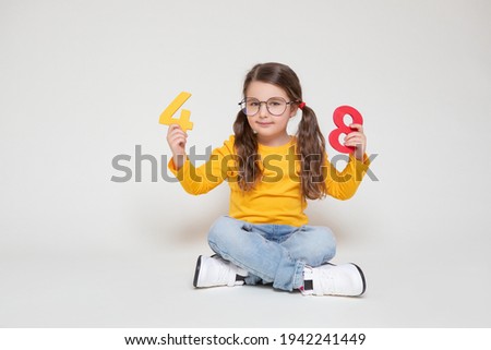 Little Child Girl Playing with Figures, early Education, Mathematics and Numeracy. Cute Girl with glasses sit legs crossed     