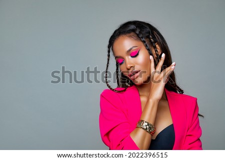 Fashion Portrait Black Woman in Pink stylish jacket. Pink Makeup curly hair and braids. Luxury Fashion model African American posing in studio against a pink wall. Beautiful black woman          