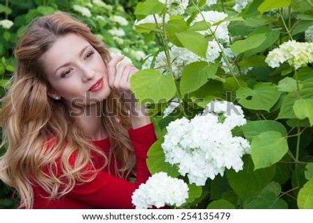 Portrait of beautiful model with white flowers in the garden, holding hands flowers