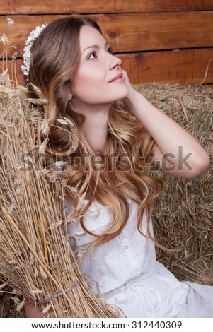 attractive  girl on the background of the loft with a stack of wheat in the hands of